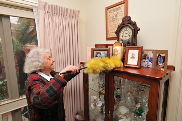Senior lady dusting crystal cabinet
